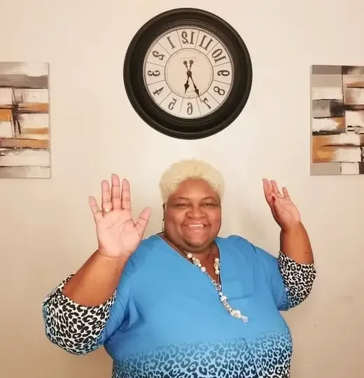 Pastor Tammy Johnson in a blue top with her hands raised in praise